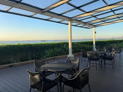 a patio with tables and chairs on a deck at Modern 2BR beside Okada Manila with Sunset View in Manila