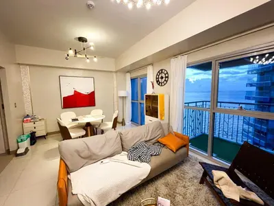 a living room with a couch and a large window at Luxurious 1BR in Bayshore w Sunset View near Okada in Manila