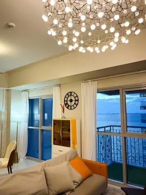 a living room with a couch and a chandelier at Luxurious 1BR in Bayshore w Sunset View near Okada in Manila