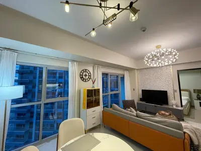 a living room with a couch and a tv at Luxurious 1BR in Bayshore w Sunset View near Okada in Manila