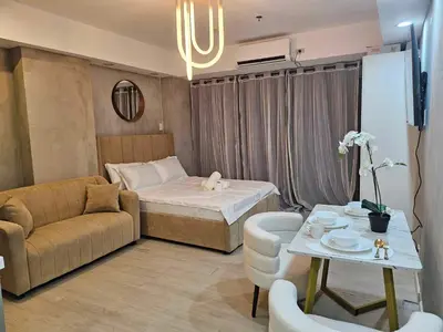a room with a bed and a couch and a table at One Bedroom at Azure Urban Near Airport in Manila