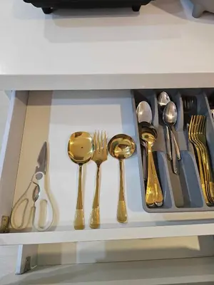 a drawer filled with gold spoons and forks and knives at One Bedroom at Azure Urban Near Airport in Manila