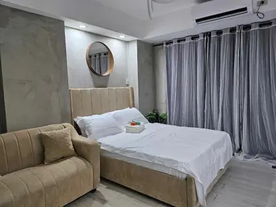 a bedroom with a bed and a couch and a mirror at One Bedroom at Azure Urban Near Airport in Manila