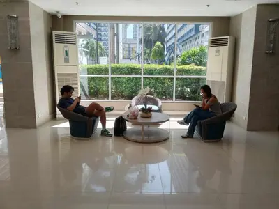 two people sitting in chairs in a lobby at Sea Residences by Sonny in Manila