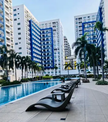 a row of benches next to a pool in a city at Sea Residences by Sonny in Manila