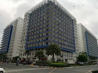 a large building with blue windows in a parking lot at Sea Residences by Sonny in Manila