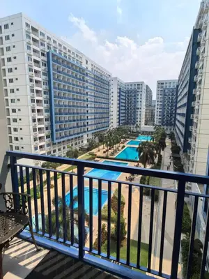 a balcony with a view of a pool and buildings at Athalia's Pad at Sea Residences in Manila
