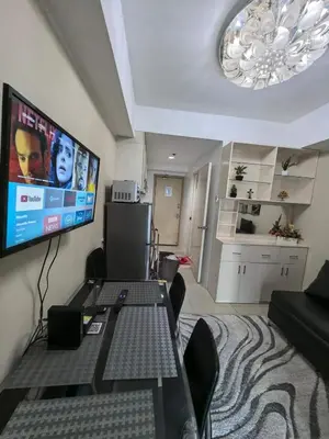 a living room with a table and a flat screen tv at Athalia's Pad at Sea Residences in Manila