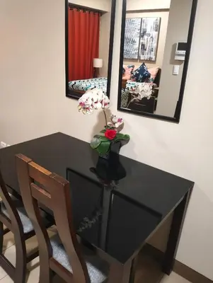 a black dining room table with two chairs and a vase with flowers at Two Palm Tree Villas by Nadz6 in Manila
