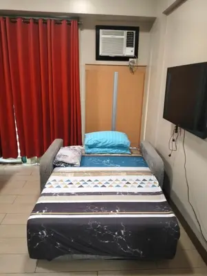 a bed in a room with a tv and red curtains at Two Palm Tree Villas by Nadz6 in Manila