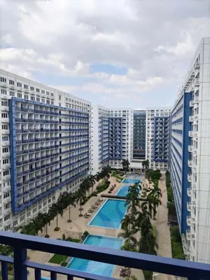 a view from a balcony of a large building with a pool at Gab's Crib - Staycation near Mall of Asia in Manila
