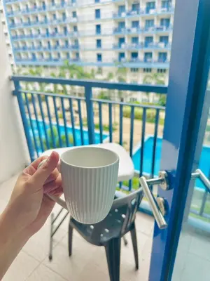 a person holding a cup on a balcony at Sea Residences by Sir Jan 0995-448-8872 in Manila