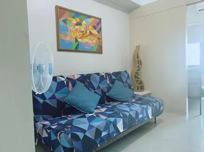 a living room with a blue couch and a painting at Sea Residences by Sir Jan 0995-448-8872 in Manila