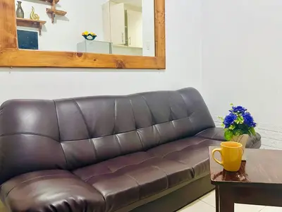 a brown leather couch in a living room with a table at Sea Residences by Sir Jan 0995-448-8872 in Manila