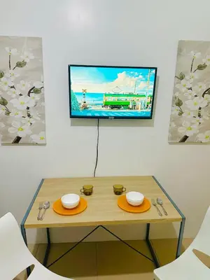a table with two plates and a tv on a wall at Sea Residences by Sir Jan 0995-448-8872 in Manila