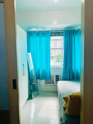 a bedroom with blue curtains and a bed and a window at Sea Residences by Sir Jan 0995-448-8872 in Manila