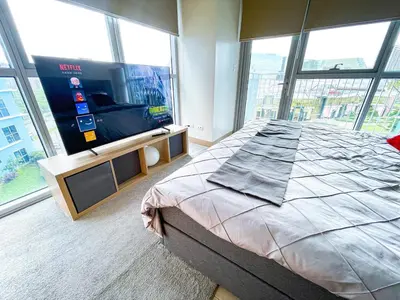 a bedroom with a large bed and a flat screen tv at Stunning 2BR across Okada Manila with Sunset View in Manila