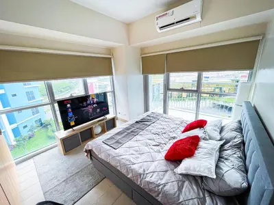 a bedroom with a bed with red pillows and a television at Stunning 2BR across Okada Manila with Sunset View in Manila