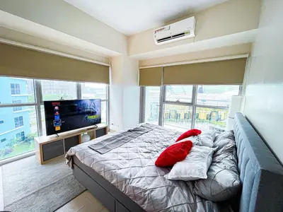 a bedroom with a bed with red pillows and a television at Stunning 2BR across Okada Manila with Sunset View in Manila