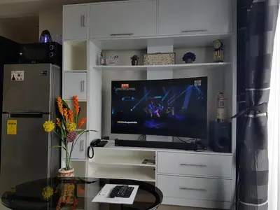 a living room with a television in a white entertainment center at Portovita North Tower 10A, 10C in Manila