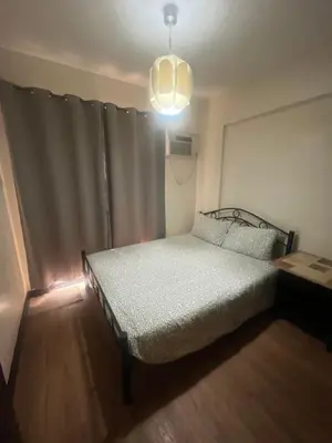 a small bedroom with a bed and a pendant light at Arista Place Condo 2 bedroom unit in Manila