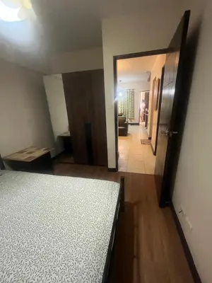 a bedroom with a bed and a living room at Arista Place Condo 2 bedroom unit in Manila