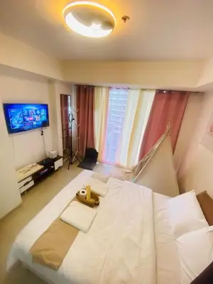 a large white bed in a room with a television at Sole Sisters Staycation in Manila