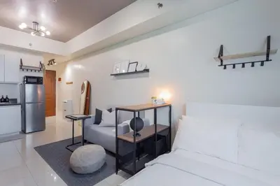 a bedroom with a bed and a couch and a kitchen at Makati Condo Near NAIA & Greenbelt - Free Parking! in Manila