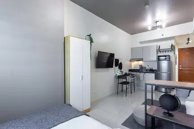 a room with a bed and a table and a kitchen at Makati Condo Near NAIA & Greenbelt - Free Parking! in Manila