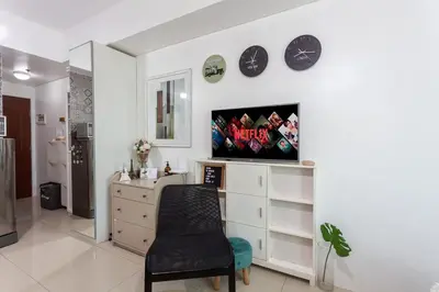a living room with a chair and a tv on a wall at Makati Condo Near Airport & Greenbelt in Manila