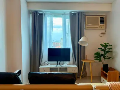 a living room with a television and a window at New Beacon Makati Condo Near Airport with Pool Access in Manila