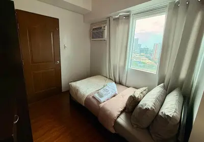 a small bedroom with a bed and a window at New Beacon Makati Condo Near Airport with Pool Access in Manila