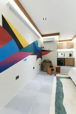 a living room with a colorful mural on the wall at The Kin House - Stay in Art Poblacion in Manila