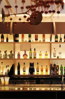 a shelf filled with lots of bottles of whiskey at The Kin House - Hotel in the Heart of Poblacion in Manila