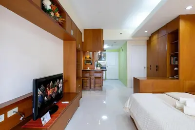 a bedroom with a bed and a flat screen tv at Relax & WFH in Vibrant & Cozy Greenbelt Condo with Pool in Manila