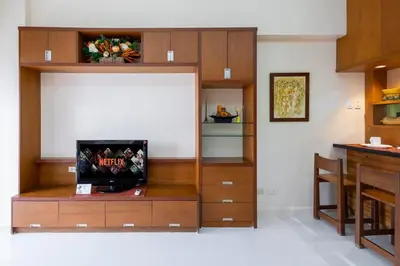 a living room with a entertainment center with a television at Relax & WFH in Vibrant & Cozy Greenbelt Condo with Pool in Manila