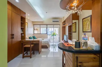 a room with a kitchen and a bedroom with a bed at Relax & WFH in Vibrant & Cozy Greenbelt Condo with Pool in Manila