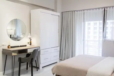 a bedroom with a bed and a desk and a mirror at NEW! Beautiful Studio in Greenbelt Makati in Manila