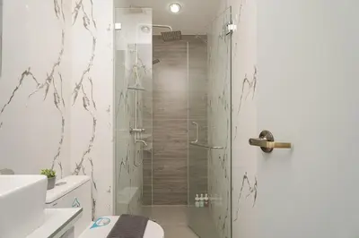 a shower with a glass door in a bathroom at NEW! Modern Condo in Greenbelt Makati with Pool & Gym in Manila