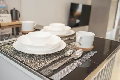 a counter with white plates and spoons on it at NEW! Modern Condo in Greenbelt Makati with Pool & Gym in Manila