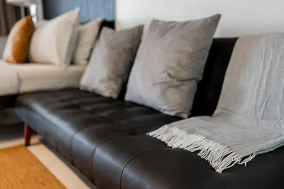 a black leather couch with pillows in a living room at NEW! Modern Condo in Greenbelt Makati with Pool & Gym in Manila