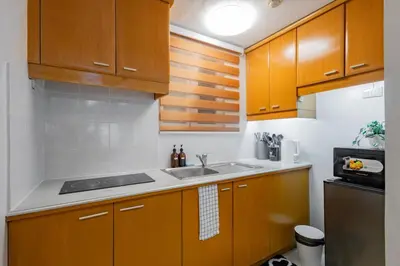 a kitchen with wooden cabinets and a sink at Charming Studio in Greenbelt Makati - Near Malls! in Manila