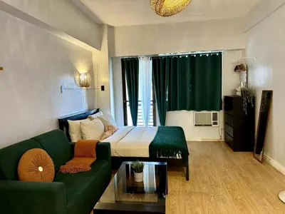 a living room with a green couch and a bed at Charming Studio in Greenbelt Makati - Near Malls! in Manila