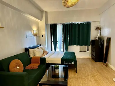 a living room with a bed and a couch in a room at Charming Studio in Greenbelt Makati - Near Malls! in Manila