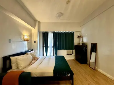 a bedroom with a large bed with a large window at Charming Studio in Greenbelt Makati - Near Malls! in Manila