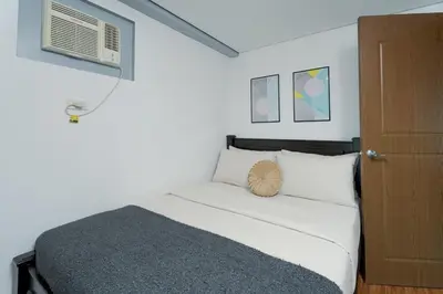 a small bedroom with a bed and a air conditioner at Free Parking! Beautiful 2BR Home in Central Makati in Manila