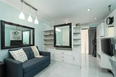 a living room with a blue couch and a television at Studio in Greenbelt Makati with Fiber WiFi & Free Pool Access in Manila