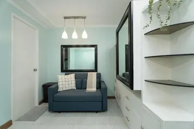 a living room with a blue chair and a mirror at Studio in Greenbelt Makati with Fiber WiFi & Free Pool Access in Manila