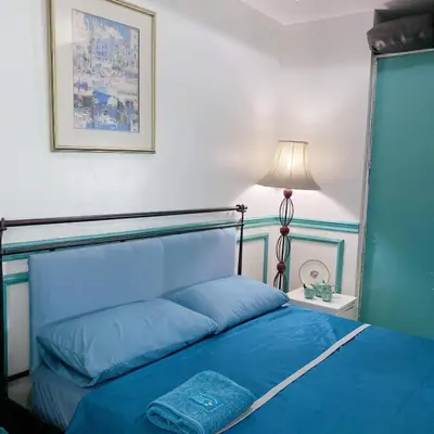 a bedroom with a blue bed with a lamp at Baywatch tower 1604 in Manila