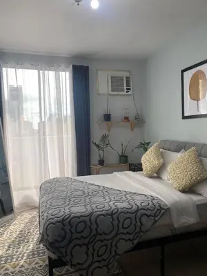 a bedroom with a bed and a large window at Ohana Buenbyahe Studio Rooms with balcony in Mandaluyong, Edsa Shaw Mrt and Megamall in Manila